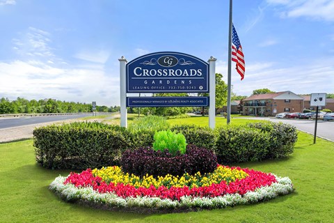 the sign for crossroads gardens in front of a flower garden