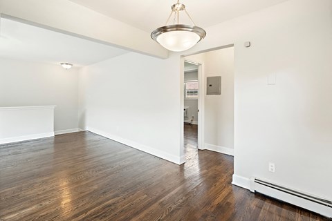 an empty living room with white walls and wood flooring