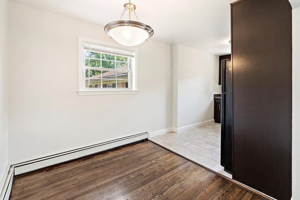 an empty room with white walls and a window and wooden floors