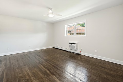 an empty living room with wood flooring and a window