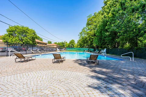 a swimming pool with reclining chairs next to a resort style pool