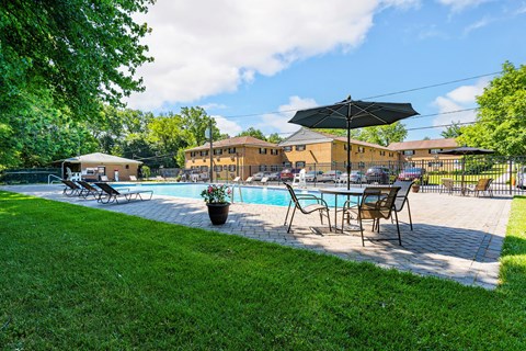 a backyard with a pool and patio with chairs and umbrellas