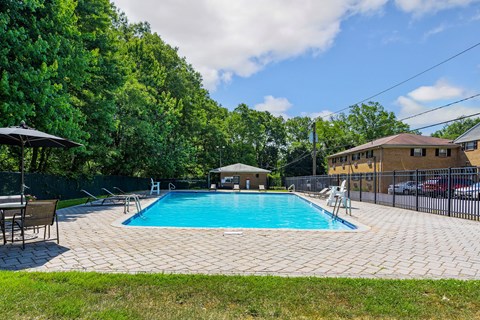 a swimming pool with chairs around it and a house in the background