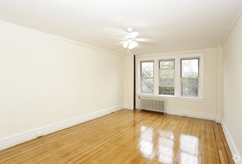 an empty living room with wood floors and a ceiling fan