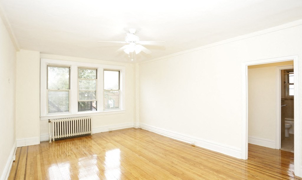 an empty living room with wood floors and a ceiling fan