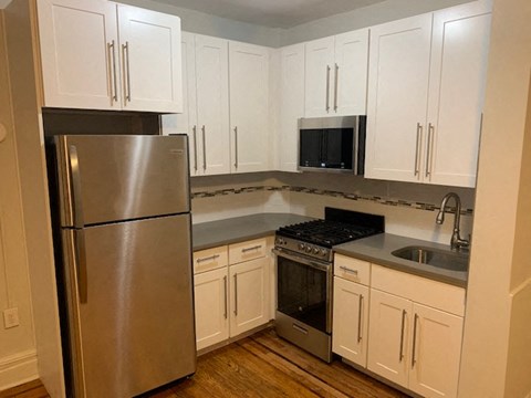 a kitchen with white cabinets and a stainless steel refrigerator