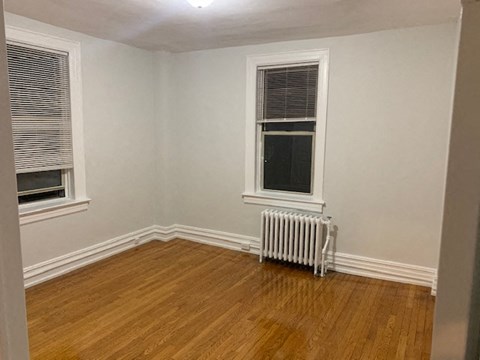 an empty room with a radiator and two windows