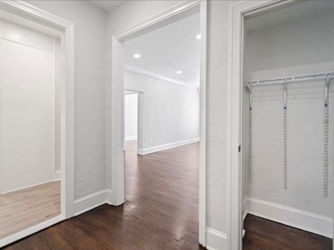 a bedroom and hallway with white walls and white closet doors