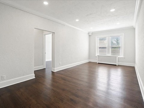 an empty living room with white walls and wood floors