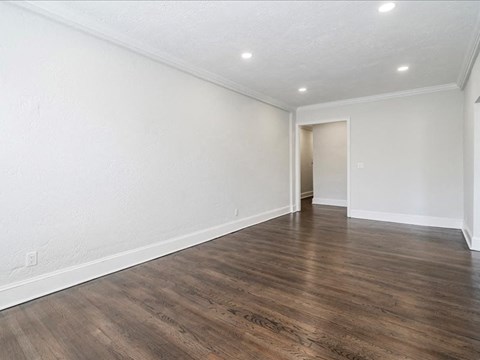 an empty living room with white walls and wood floors