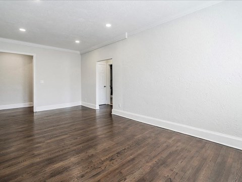 an empty living room with white walls and wood floors