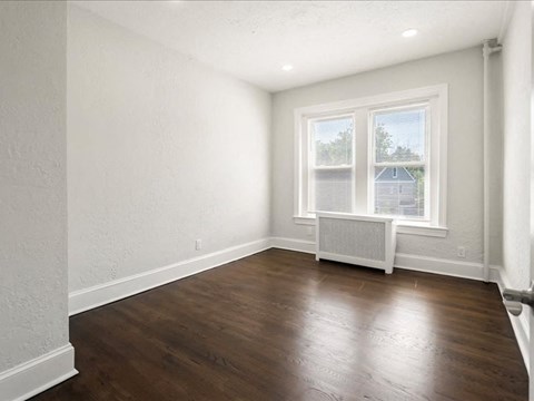 an empty living room with wood floors and a window
