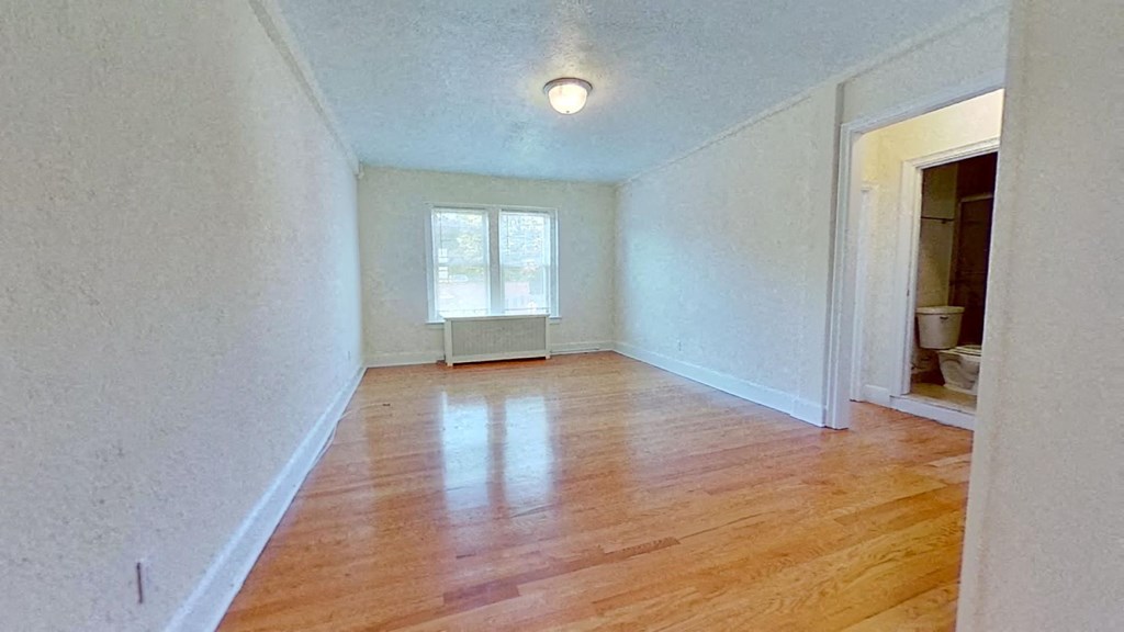 an empty living room with wood floors and a window