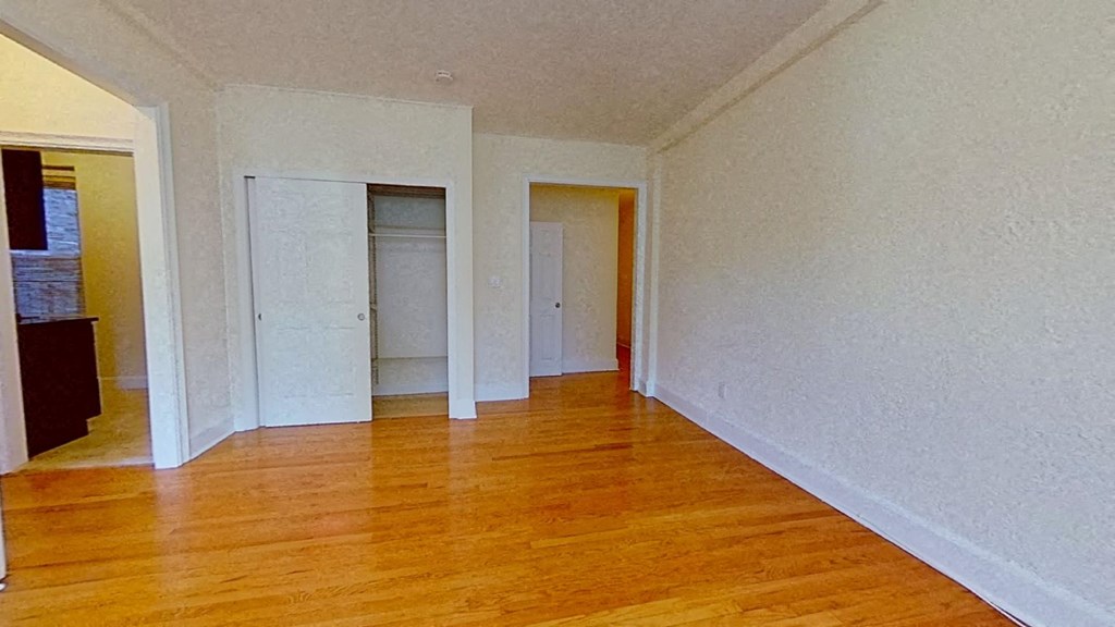 an empty living room with wood floors and white walls