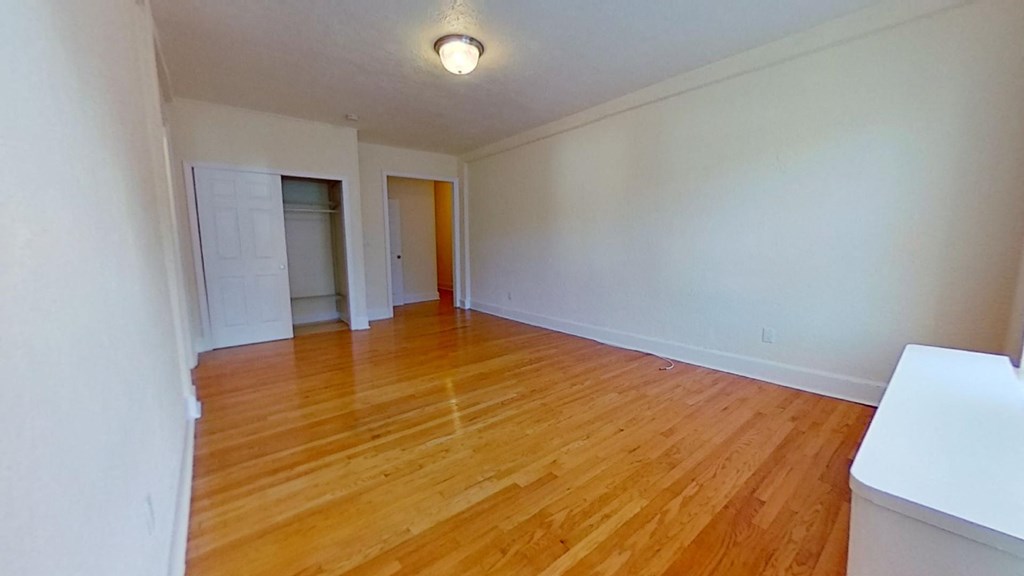 an empty living room with wood floors and white walls