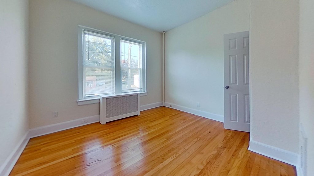 an empty living room with wood floors and a white door
