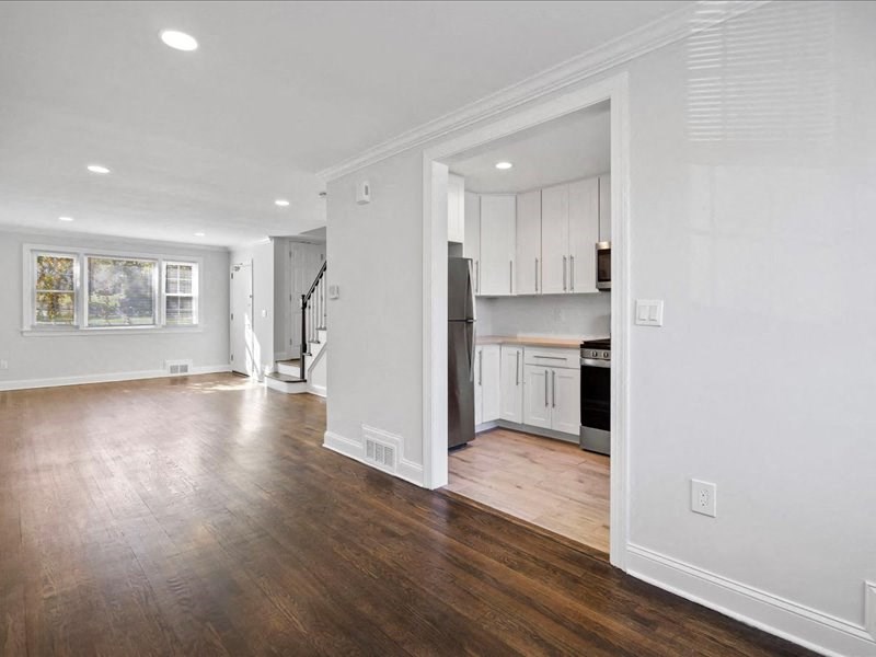 an empty living room and kitchen with wood floors