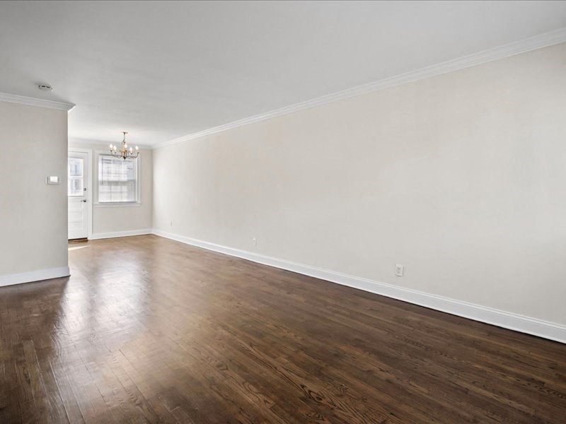 an empty living room with wood floors and white walls