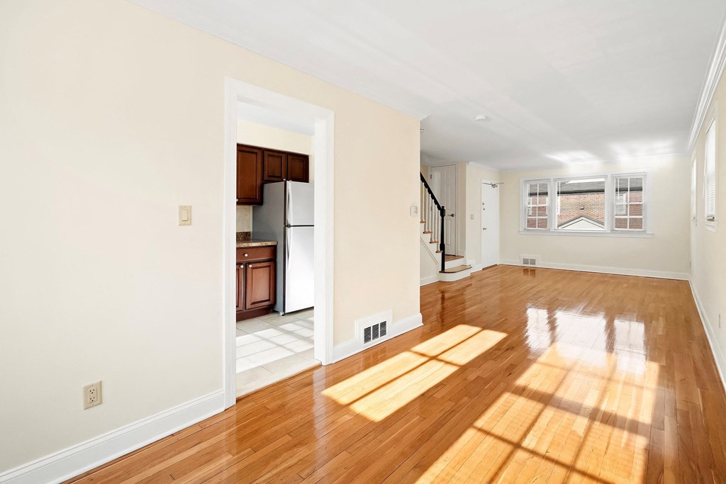 an empty living room with hardwood floors and a kitchen