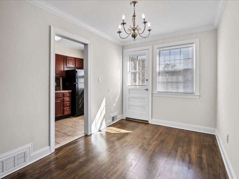a living room with a door to a kitchen and a chandelier