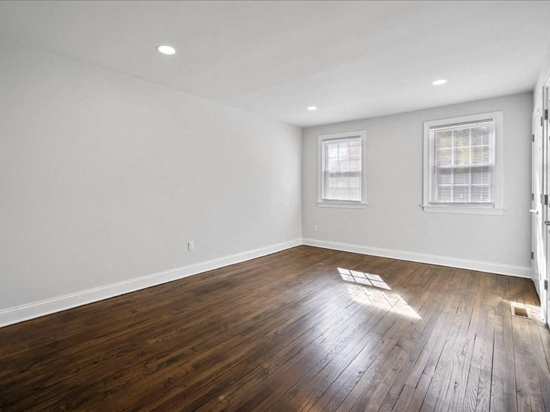an empty living room with wood floors and white walls