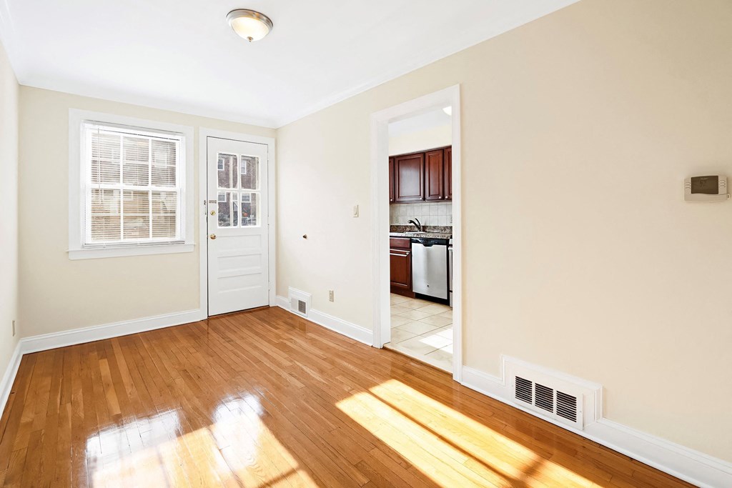 a living room with wood floors and a door to a kitchen