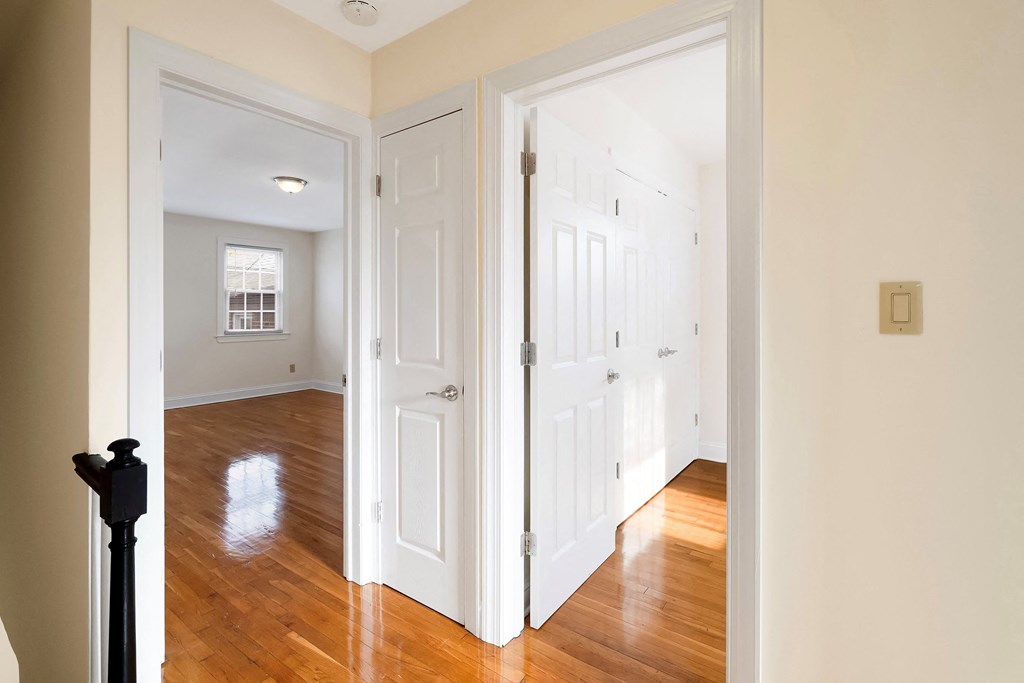 a bedroom with two closets and a hallway with wood floors