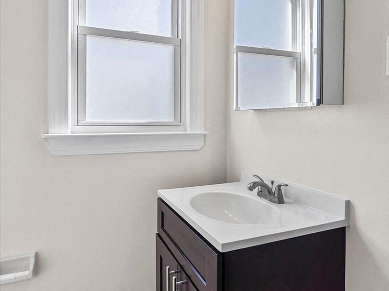 a bathroom with a sink and two windows