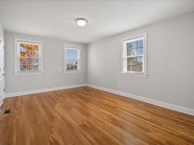 an empty living room with a wooden floor and two windows