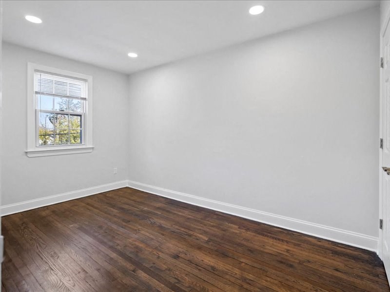 an empty room with white walls and a window and wooden floors