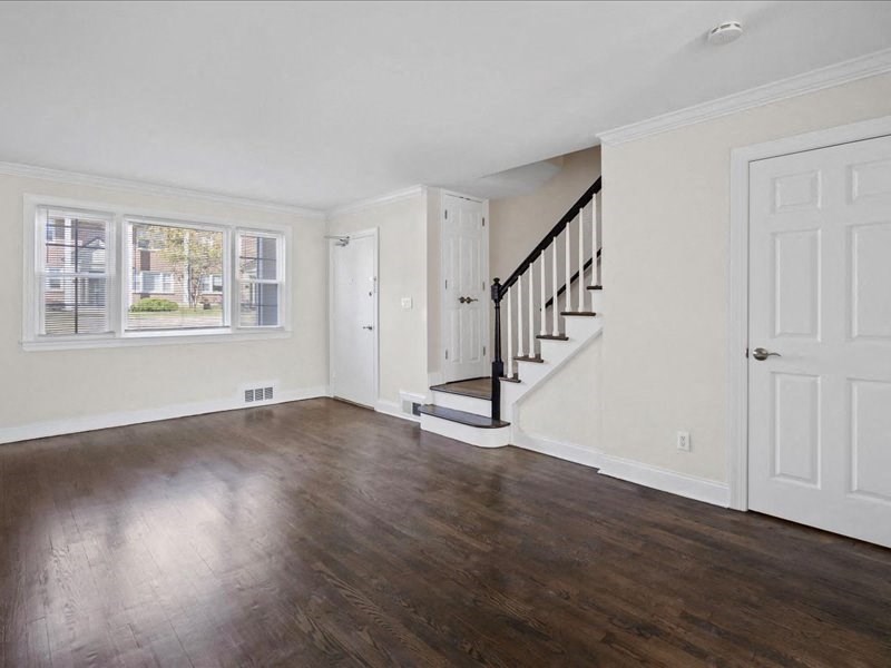 an empty living room with wood flooring and a staircase