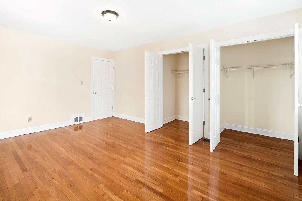 an empty room with wood floors and white closets