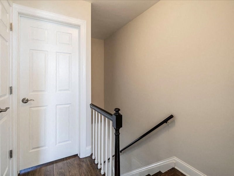 a stairwell in a home with a white door and a stair railing