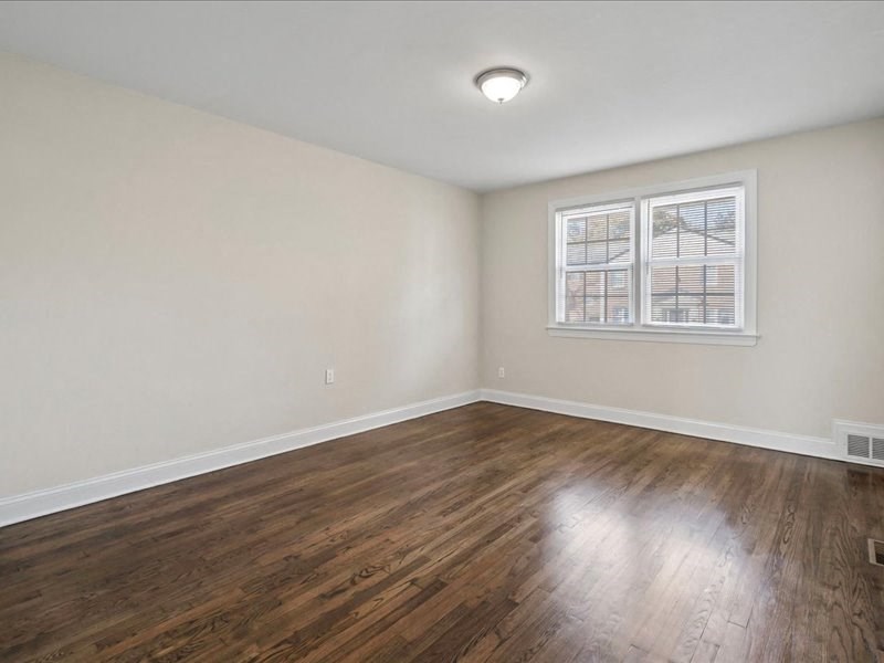 an empty living room with wood floors and a window