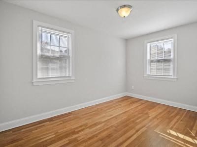 an empty bedroom with a hard wood floor and two windows