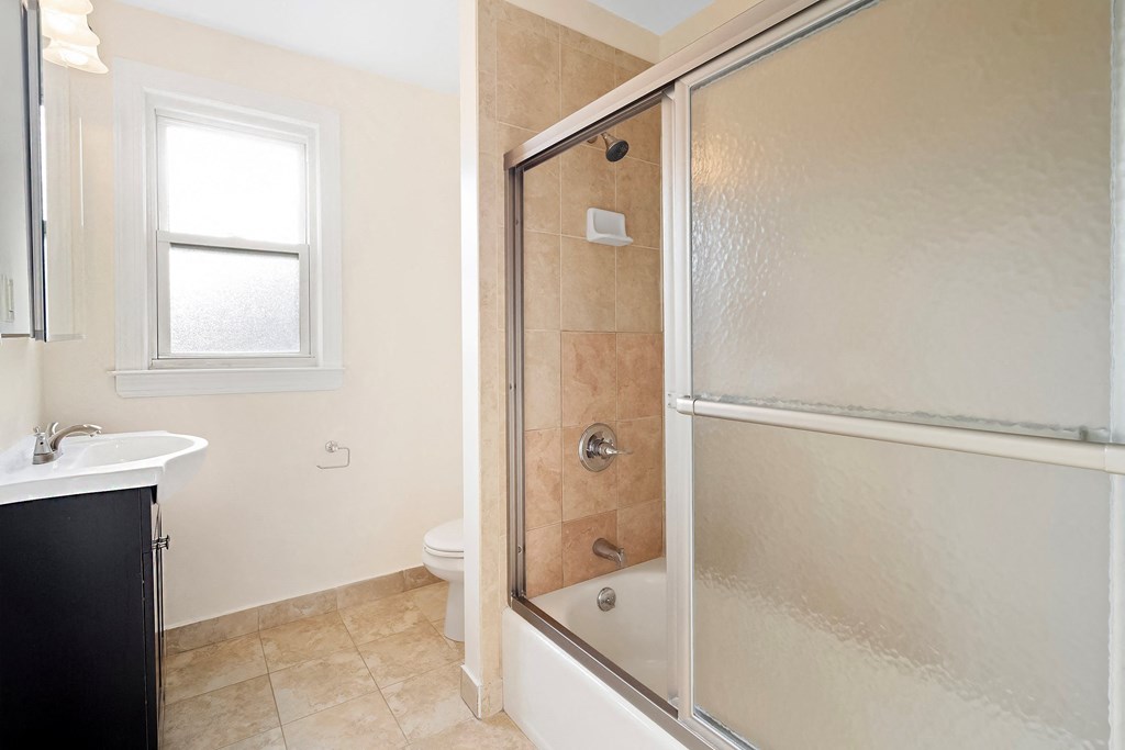 a bathroom with a shower and a sink and a window