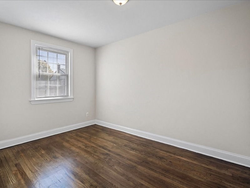 an empty room with a window and wooden floors