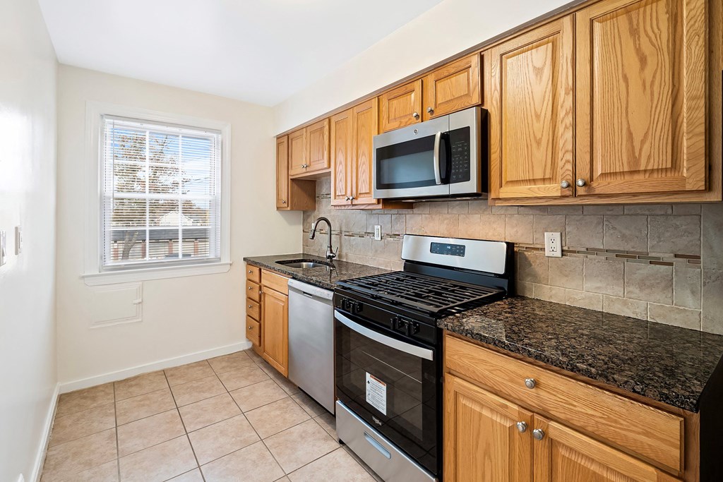 a kitchen with a stove and microwave and wooden cabinets