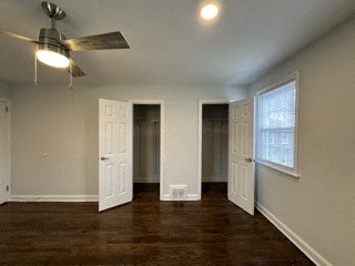 an empty living room with a ceiling fan and two doors