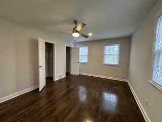 an empty living room with wood floors and a ceiling fan