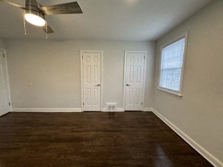 an empty living room with a wood floor and two doors
