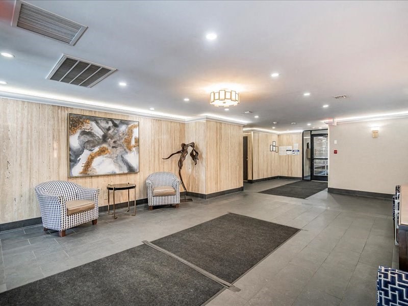 a lobby with two chairs and a painting on the wall
