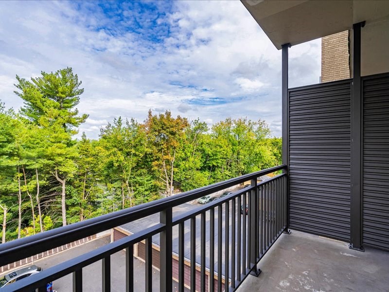 a balcony with a view of a forest and a cloudy sky
