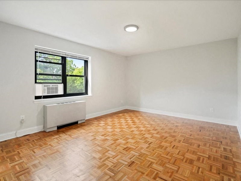 an empty room with a window and wooden floors