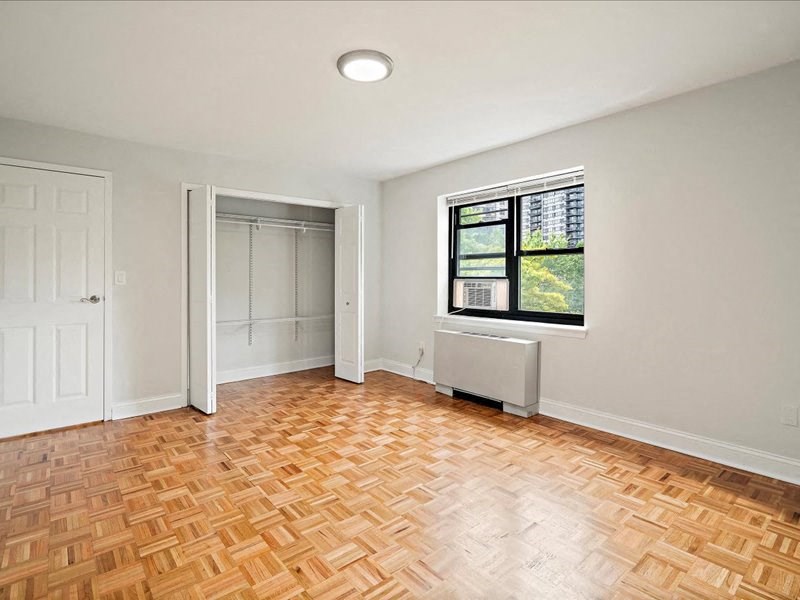 an empty living room with wood flooring and a window