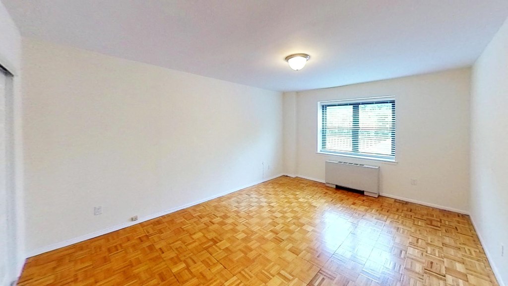 an empty living room with wood flooring and a window