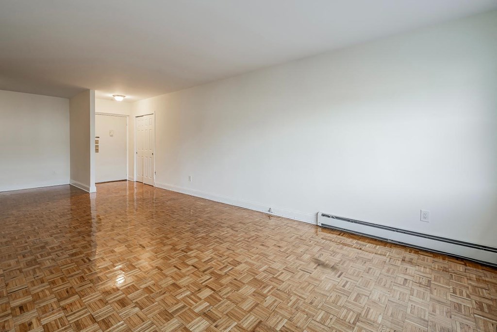 an empty living room with a wooden floor and white walls