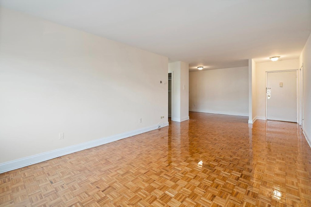an empty living room with wood flooring and white walls