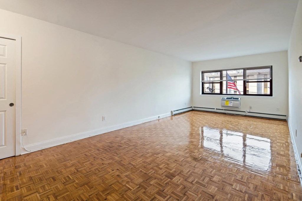 an empty living room with wood flooring and a window
