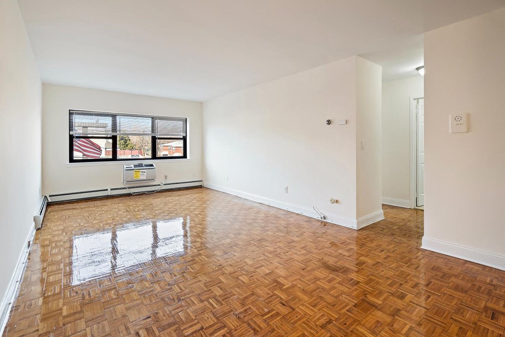 an empty living room with wood floors and a window